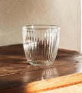Retro Striped Glass Cup catching warm sunset light on wood